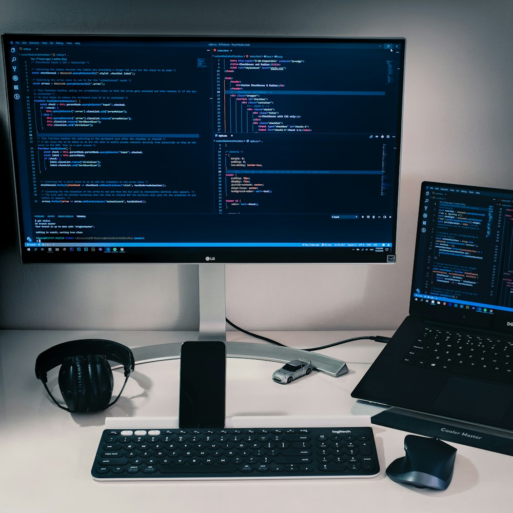 A laptop beside a desktop monitor, with a keyboard and mouse on a desk